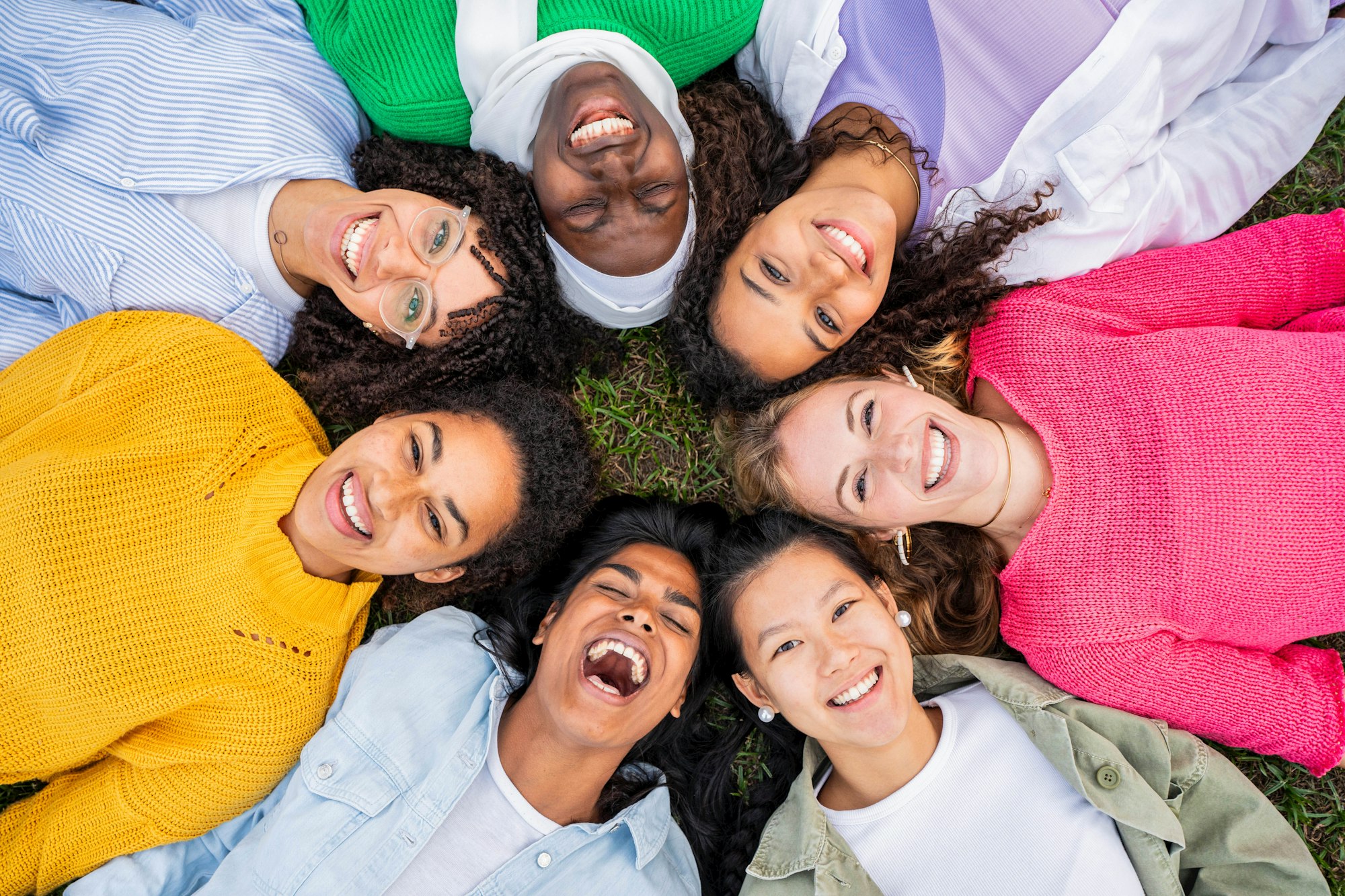 Multiracial group of young women in circle smiling at camera together